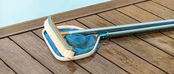 Pool brush and net laying next to a pool