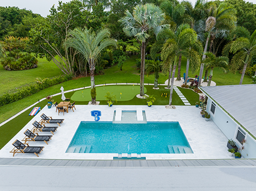 Custom in ground pool with stone patio and backyard landscape design from CoastLife Pools South Florida