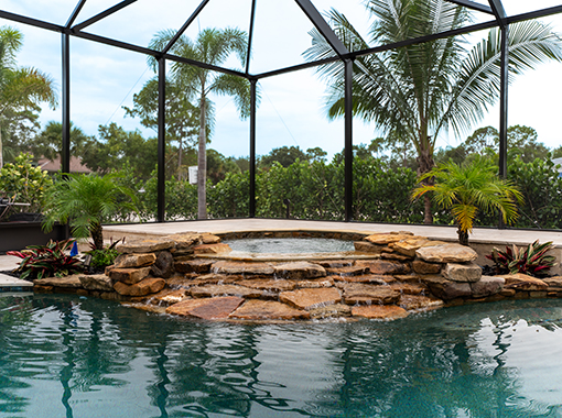 Custom in ground pool and spa with stone waterfall and tropical plants from CoastLife Pools South Florida